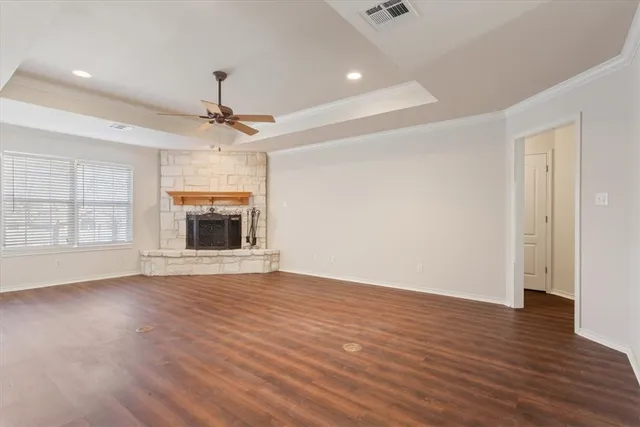 an empty room with wooden floor fireplace and windows