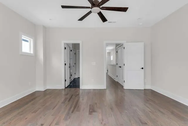 a view of empty room with wooden floor and ceiling fan