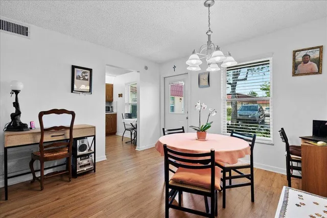 a dining room with wooden floor a chandelier a wooden table and chairs