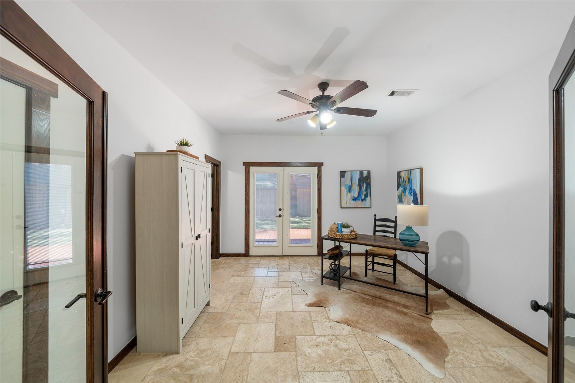 2601 Bevis Street, Unit E Houston, TX 77008 - Photo 6 of 47 Versatile first-floor bedroom featuring natural stone
flooring, warm wood trim, and French doors that open to
the backyard patio, filling the space with natural light.
Ideal for a guest suite, home office, or private retreat.