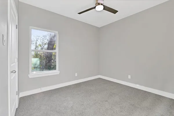 an empty room with a window and a ceiling fan