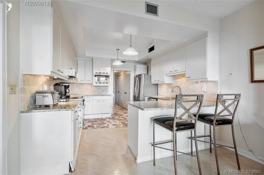 2824 Southeast Dune Drive, Unit 2102 Jensen Beach, FL 34957 - Photo 12 of 40 a kitchen with stainless steel appliances kitchen island granite countertop a sink and cabinets