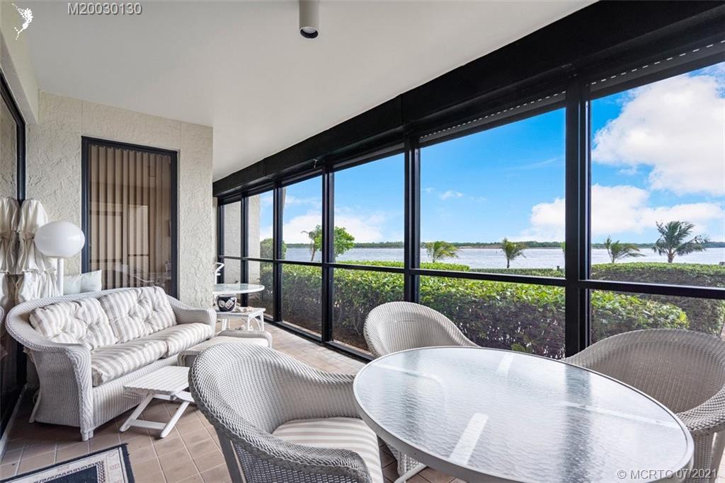 2824 Southeast Dune Drive, Unit 2102 Jensen Beach, FL 34957 - Photo 26 of 40 a dining room with furniture a flat screen tv and a floor to ceiling window