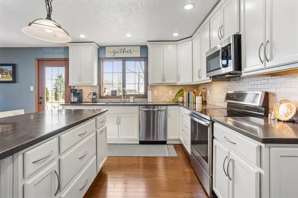 a kitchen with stainless steel appliances granite countertop a sink and dishwasher a stove top oven with wooden floor