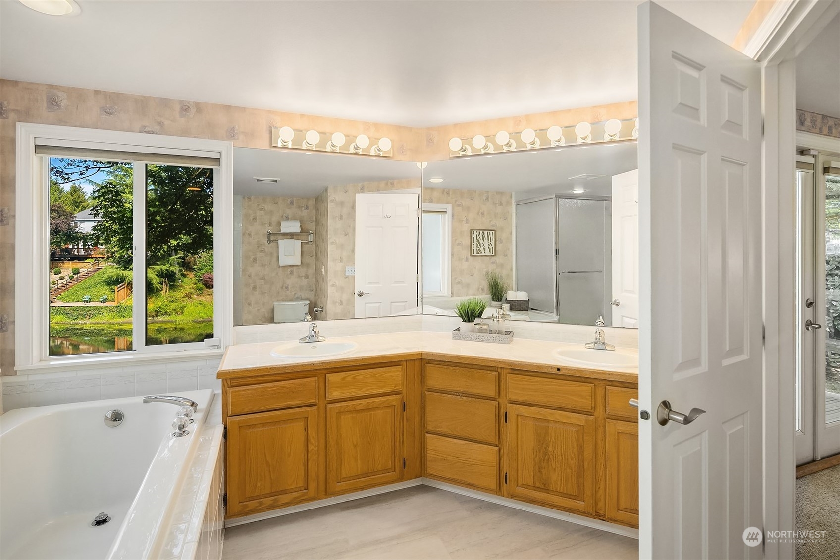 11302 East Riverside Drive Bothell, WA 98011 - Photo 29 of 37 a spacious bathroom with a double vanity sink a large mirror a bathtub and next to a window