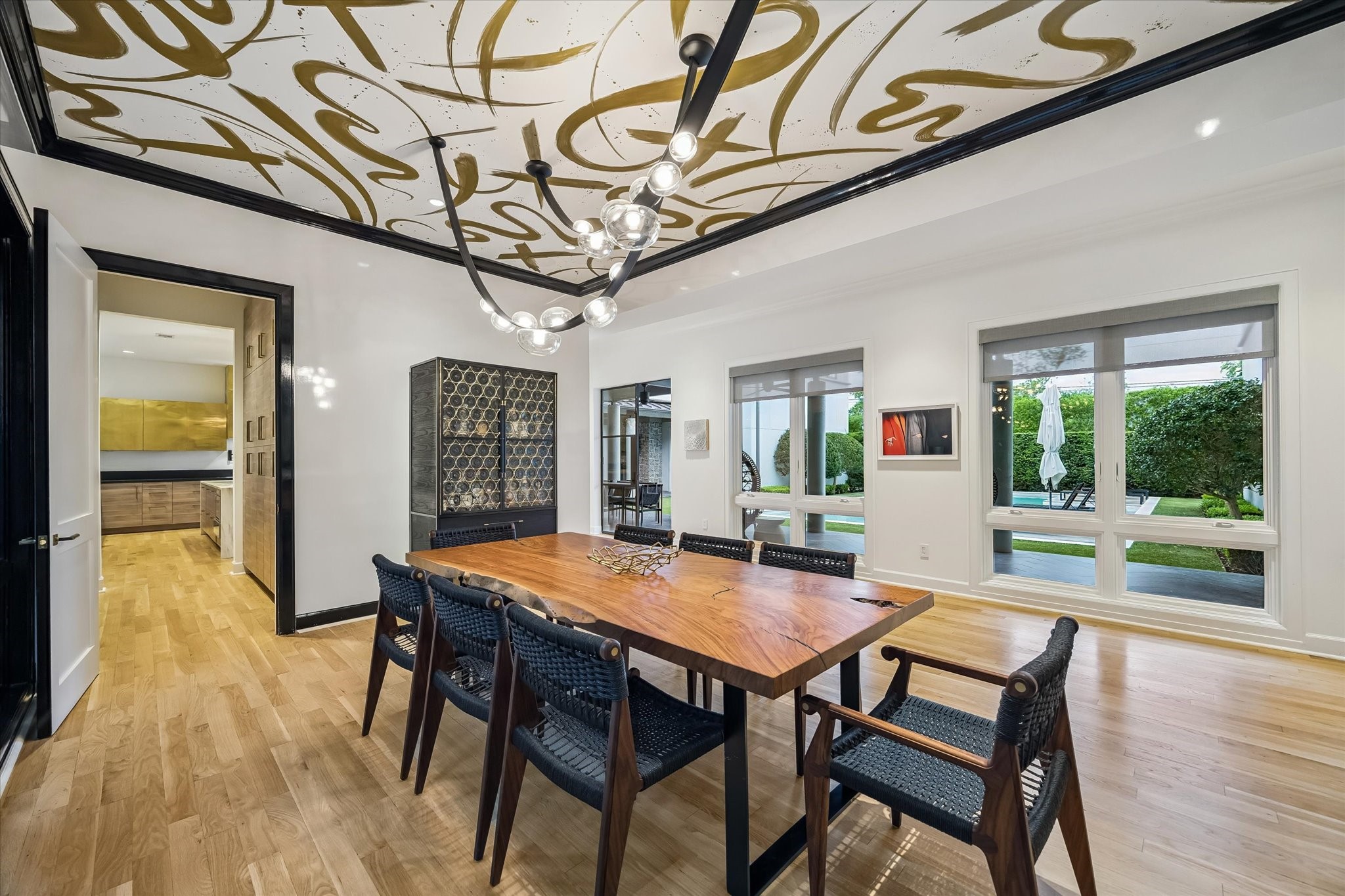 3706 Tangley Street Houston, TX 77005 - Photo 13 of 50 A custom ceiling mural by Carolyn Lizarraga creates an artful focal point, setting a refined and memorable tone for the space. Neutral lacquer walls and crown molding with black trim add depth and contrast. It’s a dining room designed to feel both elevated and inviting.