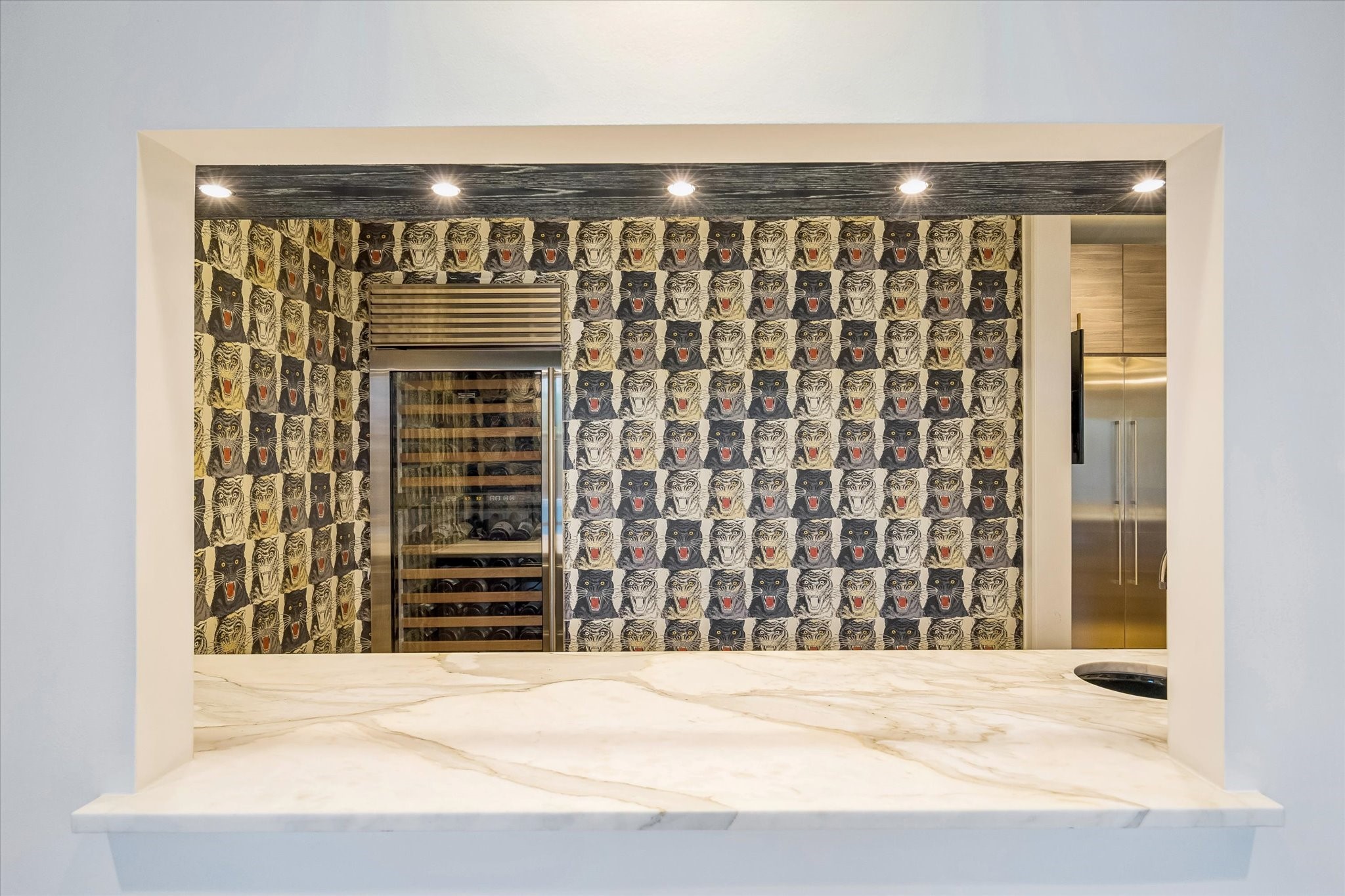 3706 Tangley Street Houston, TX 77005 - Photo 17 of 50 The wine/wet bar is beautifully appointed with a marble countertop, brushed brass hardware, and custom cabinetry for a refined, tailored finish. Sub-Zero refrigeration, a wine column, and a Hoshizaki crushed ice maker provide a full-service beverage experience. Designer wallpaper and recessed lighting add a sophisticated, intimate atmosphere.