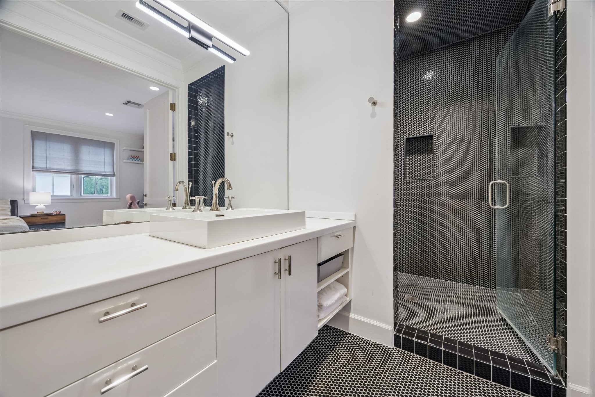 3706 Tangley Street Houston, TX 77005 - Photo 40 of 50 Complementing Guest Bedroom No. 3, this bathroom features penny tile flooring and a shower finished with black penny tile and a built-in niche. Floating cabinetry with a white stone countertop and vessel sink adds a modern edge. A separate water closet with Toto commode enhances functionality.