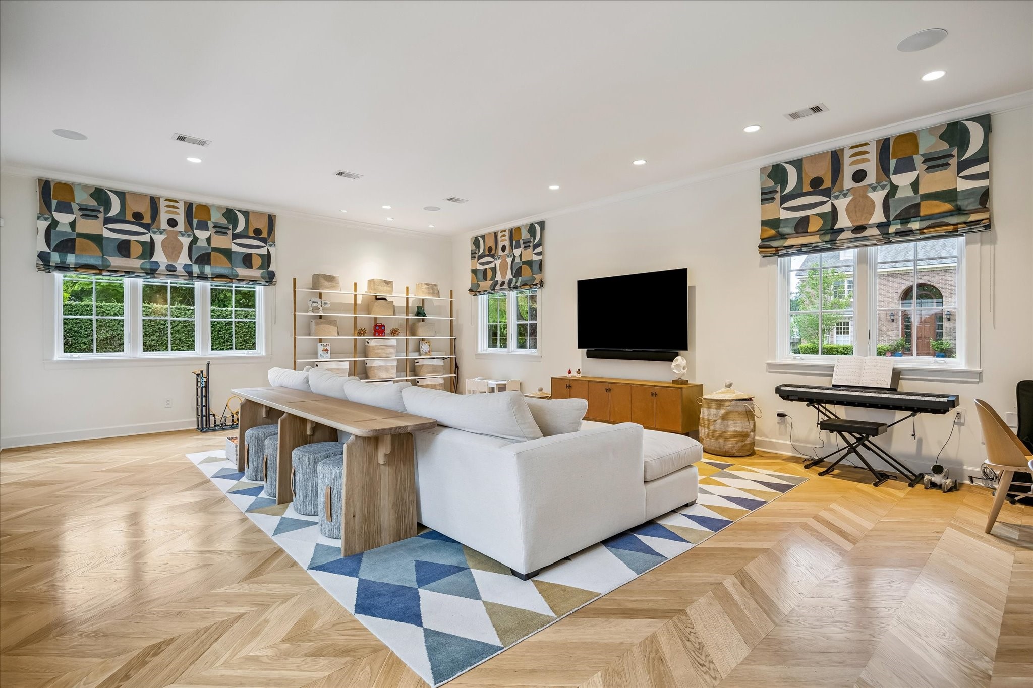 3706 Tangley Street Houston, TX 77005 - Photo 6 of 50 Light oak hardwoods and soft neutral tones create a warm, inviting foundation in this expansive family room. Recessed LED lighting and custom window treatments elevate the space without overwhelming it. It’s designed for both everyday comfort and effortless gathering.
