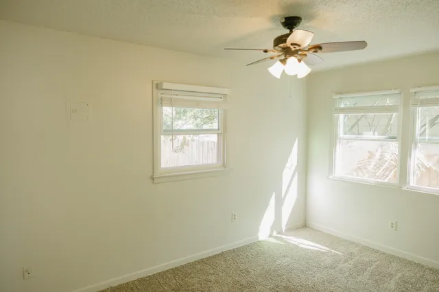 a view of a room with a ceiling fan and window