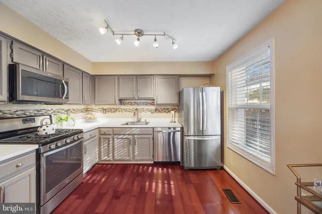 a kitchen with a sink wooden floor and stainless steel appliances