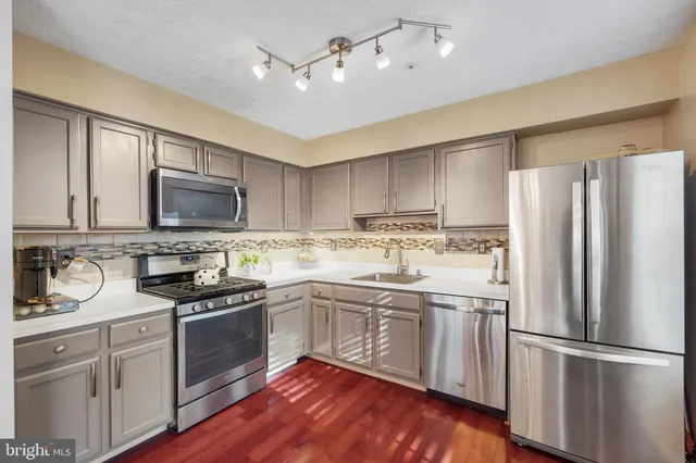 a kitchen with a refrigerator stove and sink with wooden floor