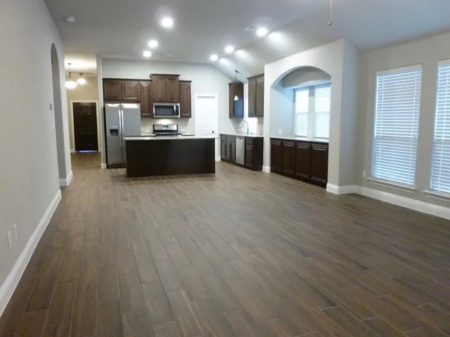a view of kitchen with kitchen island wooden floor and stainless steel appliances