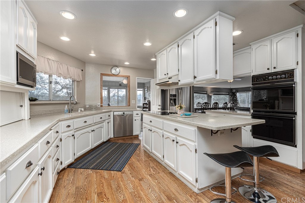 45943 Black Oak Road Coarsegold, CA 93614 - Photo 26 of 64 a kitchen with stainless steel appliances granite countertop a stove top oven a sink dishwasher and white cabinets with wooden floor
