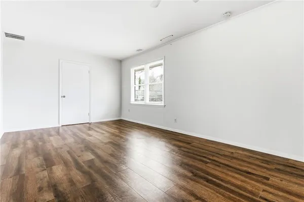 an empty room with wooden floor and windows