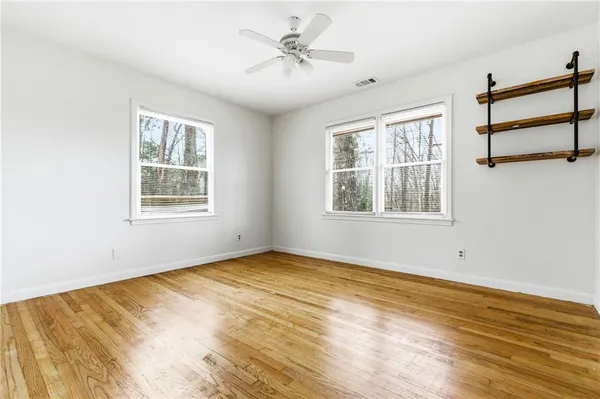 a view of an empty room with a window and wooden floor