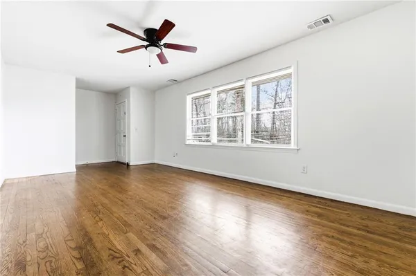 an empty room with wooden floor and windows