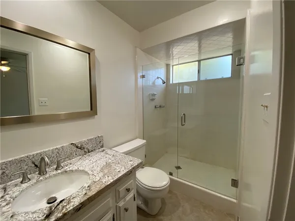 a bathroom with a granite countertop sink mirror vanity and toilet