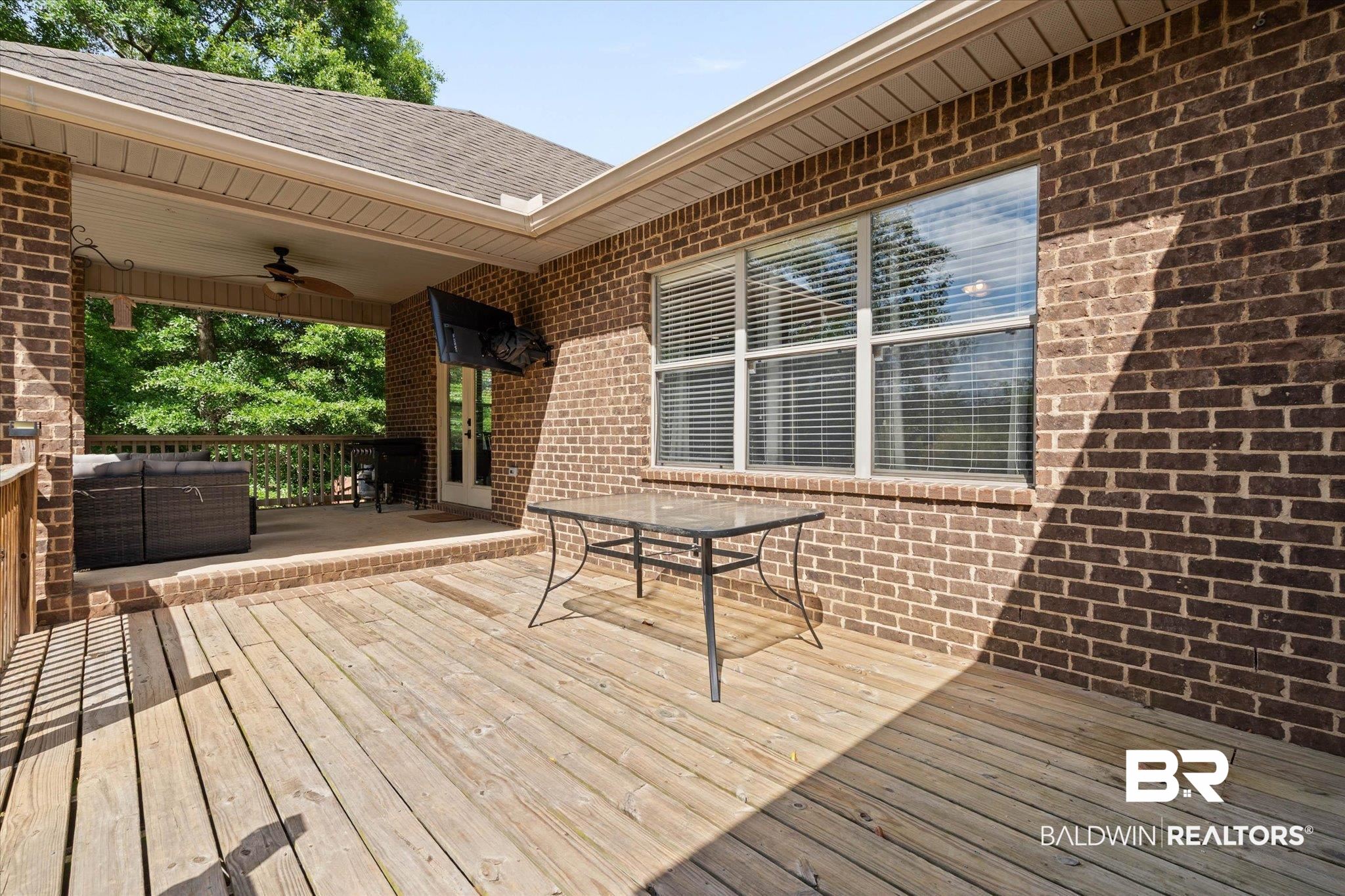 3739 Whitestone Drive Semmes, AL 36575 - Photo 21 of 25 Expansive outdoor deck featuring wood-finish flooring, a covered patio with a ceiling fan, brick exterior, and multiple windows with blinds