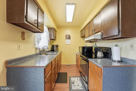 a kitchen with stainless steel appliances granite countertop a sink a stove and a wooden floors