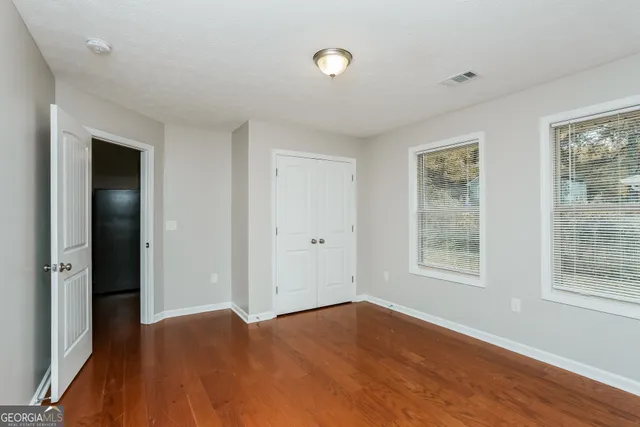 a view of an empty room with wooden floor and a window