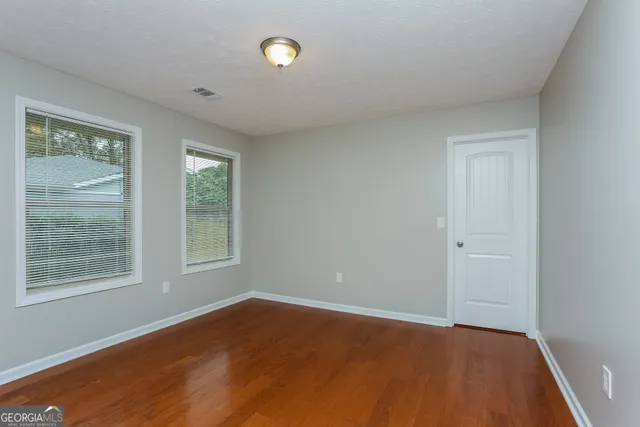 an empty room with wooden floor and windows