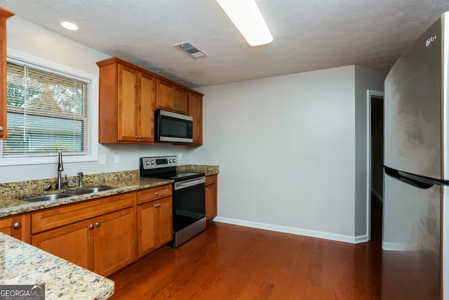 a kitchen with stainless steel appliances granite countertop a refrigerator a stove top oven a sink and dishwasher