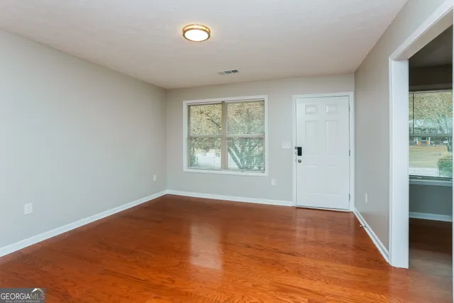 an empty room with wooden floor and windows