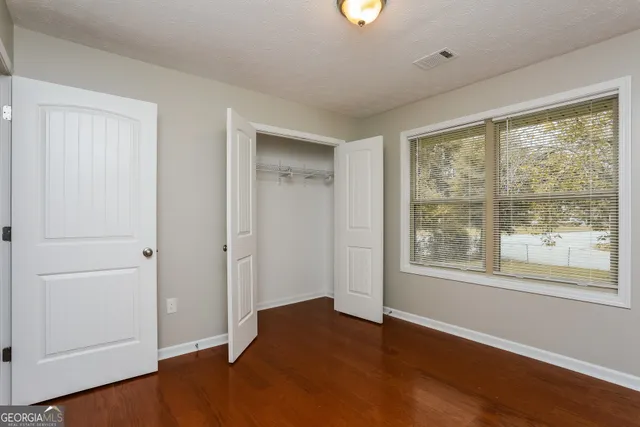a view of an empty room with wooden floor and a window