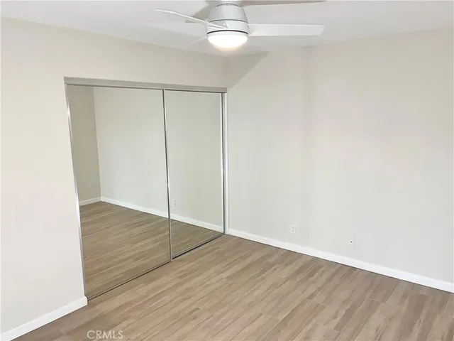 an empty room with wooden floor closet and windows