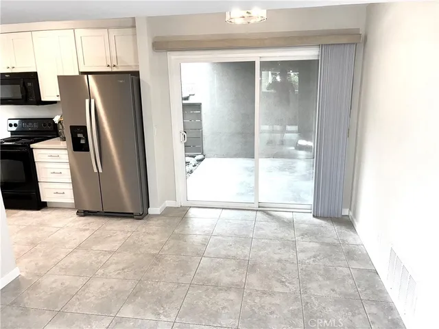 a view of a refrigerator in kitchen and an empty room