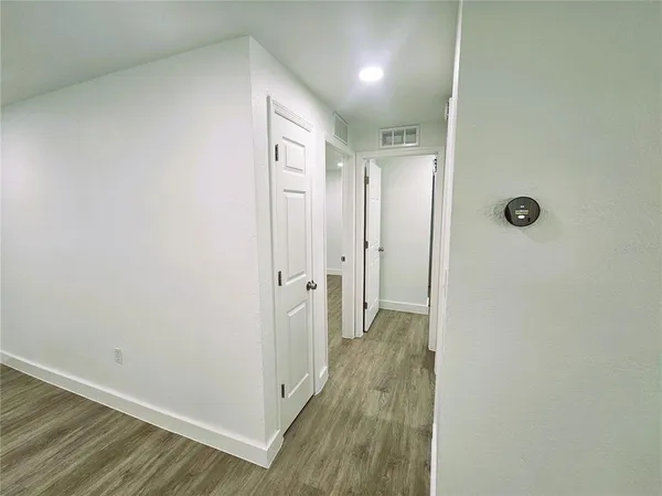 a view of an empty room with wooden floor and closet