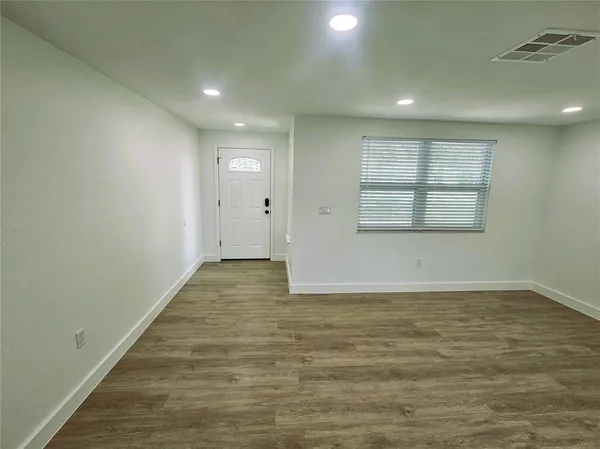 a view of an empty room with wooden floor and a window