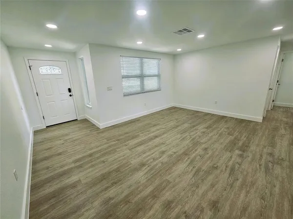 an empty room with wooden floor and windows