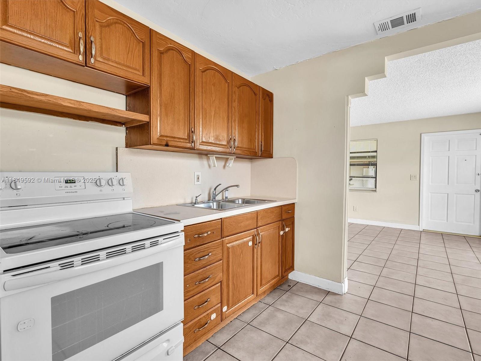 5611 Southwest 37th Street, Unit 1 Davie, FL 33314 - Photo 25 of 46 a kitchen with a stove top oven sink and cabinets
