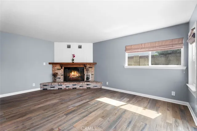 a view of an empty room with wooden floor and a fireplace