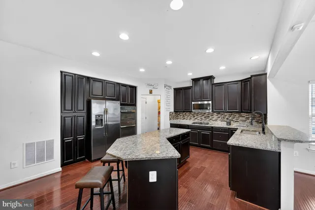 a kitchen with kitchen island granite countertop stainless steel appliances lots of counter top space and refrigerator
