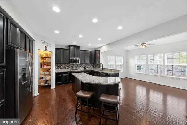 a living room with stainless steel appliances kitchen island a flat screen tv and a large window