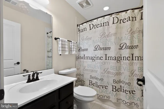 a bathroom with a granite countertop double vanity sink mirror and toilet