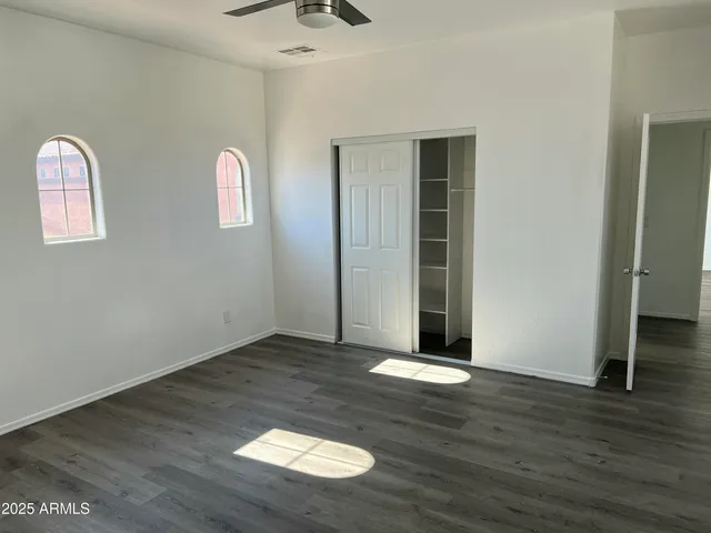 an empty room with wooden floor and windows