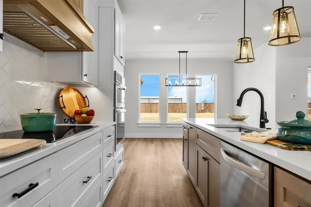 a kitchen with stainless steel appliances granite countertop a sink a stove and a wooden floors