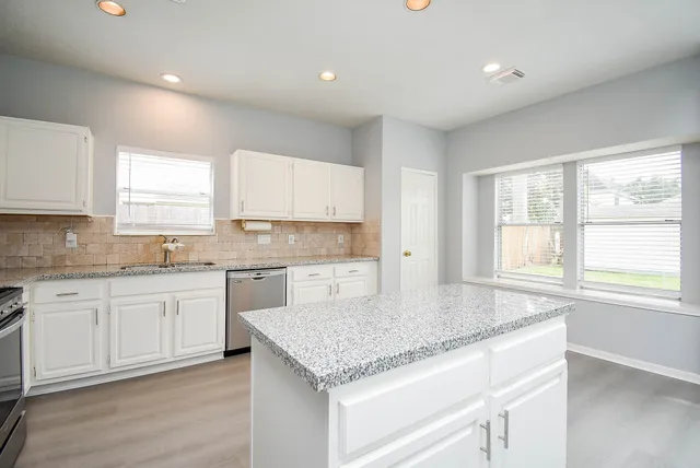 a kitchen with granite countertop stainless steel appliances a sink stove and cabinets