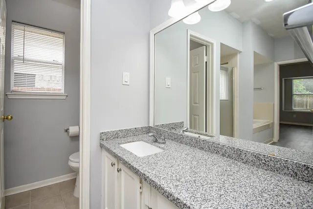 a bathroom with a granite countertop sink and a mirror