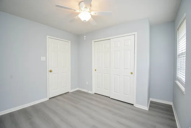 an empty room with wooden floor and windows