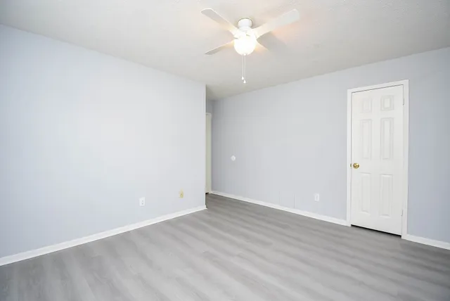 an empty room with wooden floor and ceiling fan