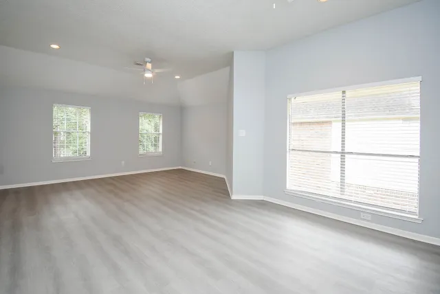a view of an empty room with wooden floor and a window