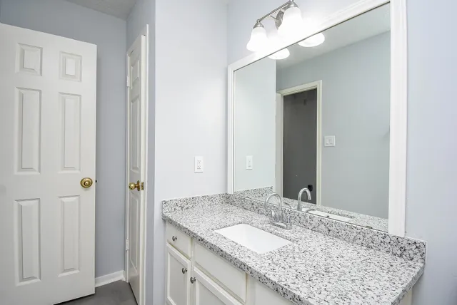 a bathroom with a granite countertop sink and a mirror
