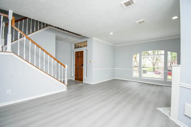 a view of an empty room with wooden floor and fan