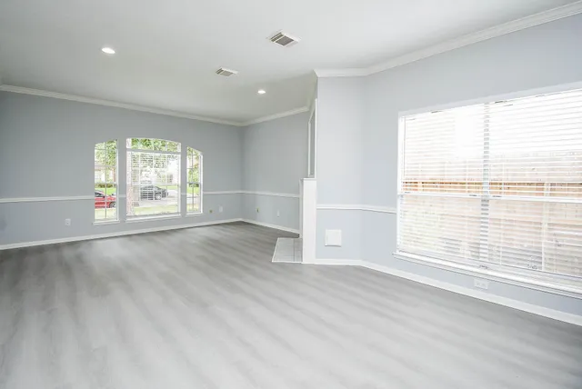 an empty room with wooden floor and windows