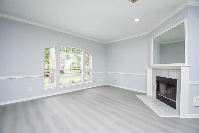 an empty room with wooden floor fireplace and windows